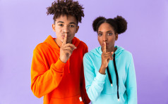 Photo of young african american guy and girl holding index fingers on lips meaning shh isolated over violet background