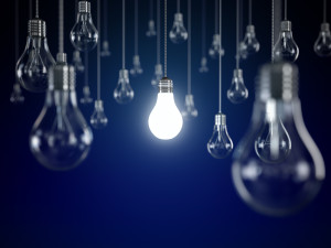 Hanging light bulbs with glowing one isolated on dark blue background
